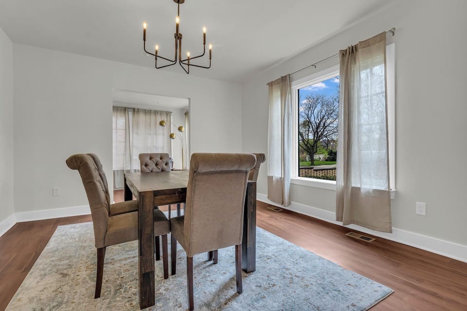 Inviting dining room featuring a wooden table & modern chandelier