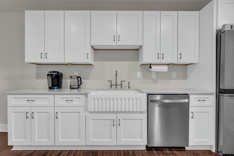 Bright, minimalist kitchen featuring sleek white cabinets &  modern appliances