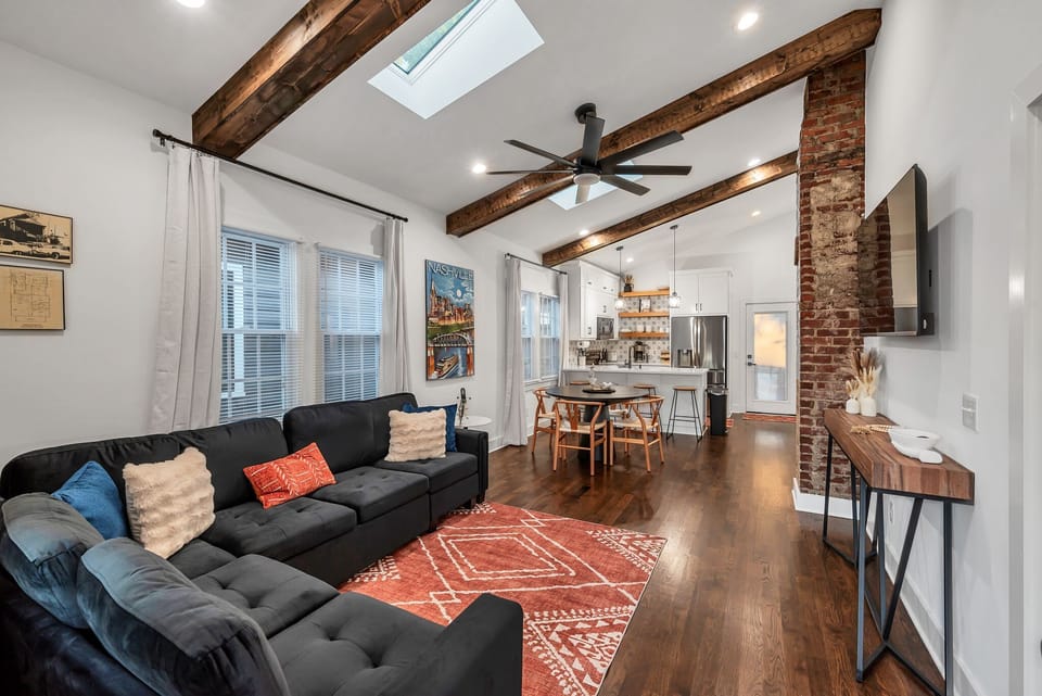Living area with skylights, exposed beams, and exposed brick
