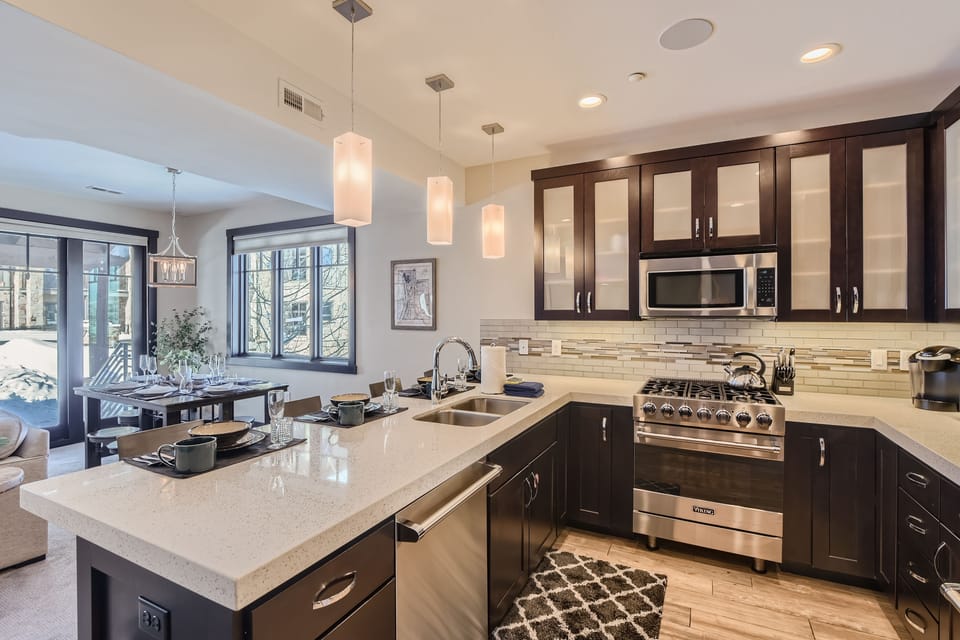 This modern open-concept living space features a fully equipped kitchen with sleek cabinetry and a spacious dining island—the perfect hub for shared mountain meals and social gatherings.