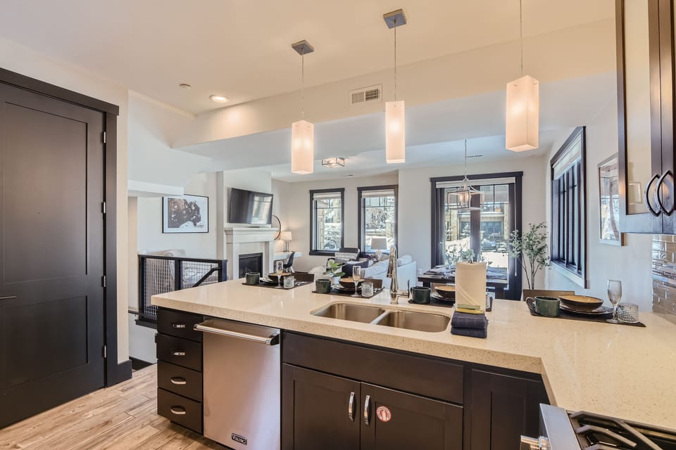 This modern open-concept living space features a fully equipped kitchen with sleek cabinetry and a spacious dining island—the perfect hub for shared mountain meals and social gatherings.