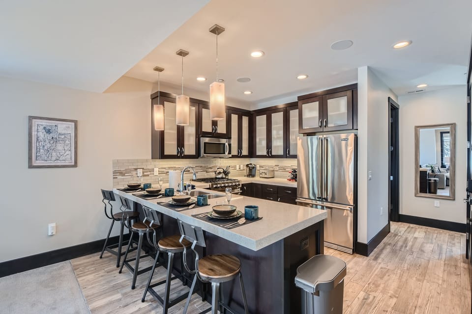 This modern open-concept living space features a fully equipped kitchen with sleek cabinetry and a spacious dining island—the perfect hub for shared mountain meals and social gatherings.