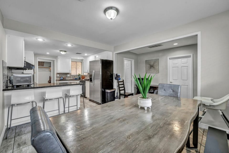 This dining area blends elegance and functionality, featuring a rustic wooden table, cozy seating, and a seamless flow to the fully equipped modern kitchen.