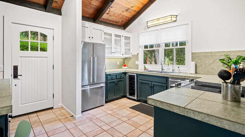 Beautiful kitchen equipped with an electric stove, wine fridge and large fridge and freezer.