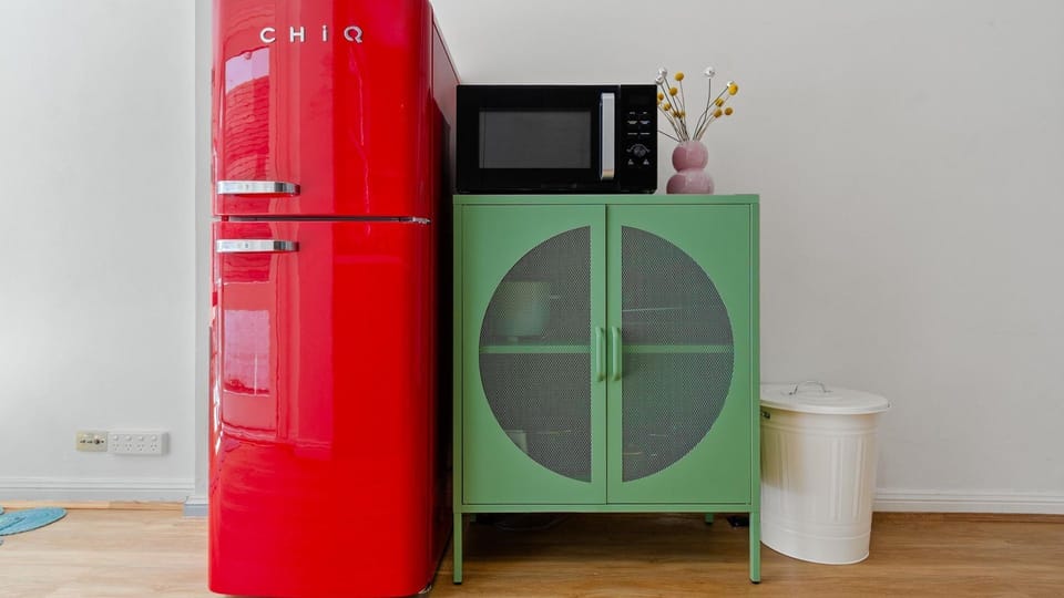 Colourful kitchen with a red fridge and green cabinetry.