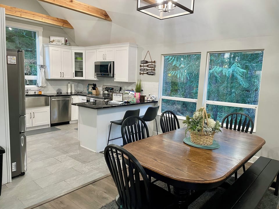 Open floor plan with the dining table looking out in the woods and firepit. 