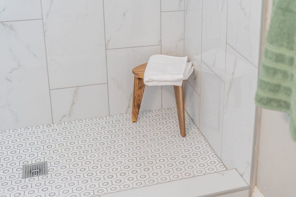 Stylish teak wood stool adding a touch of elegance to the bathroom.
