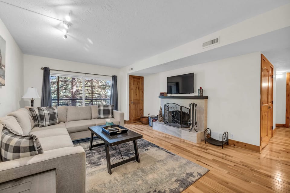 Living Room: L-shaped sleeper couch, a wood-burning fireplace, 55” Smart TV w/cable, access to the balcony 
