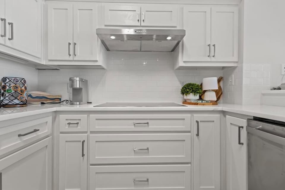 This kitchen features sleek white cabinetry, modern appliances, and a stylish countertop, perfect for culinary adventures