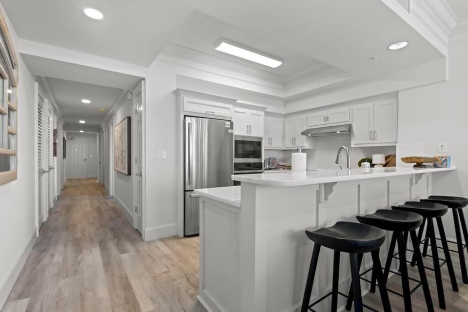 This kitchen features sleek stainless appliances, white cabinetry, and a breakfast bar, perfect for casual dining