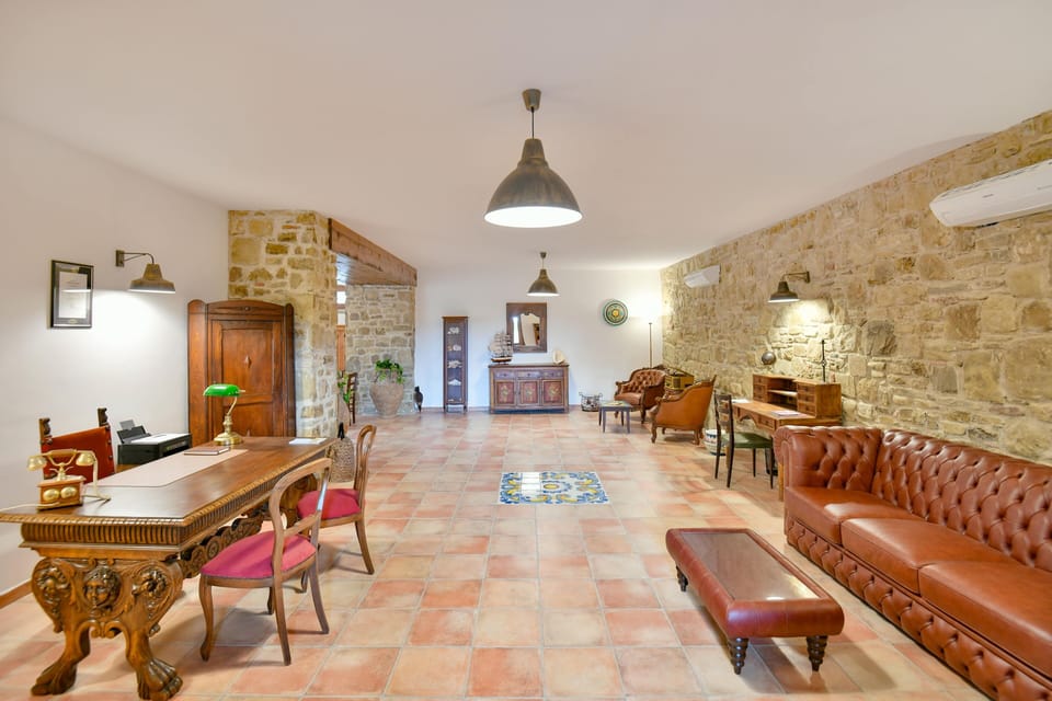 Charming lounge: vintage leather, wood decor, terracotta tiles & stone walls.
