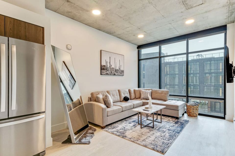 Inviting living area with a plush sectional, large windows, and floor-length mirror, perfect for relaxing or entertaining 🌿🛋️✨
