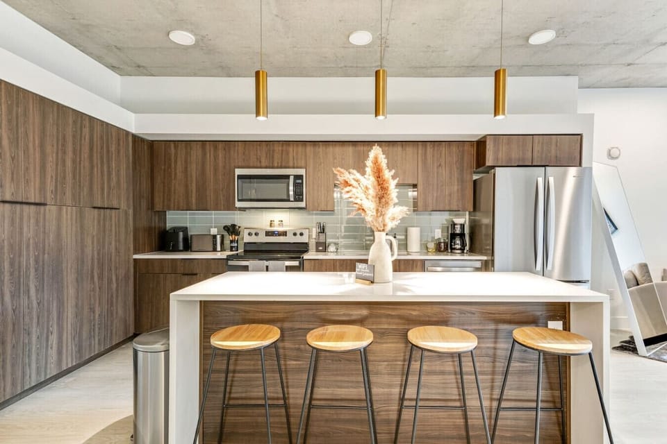 Contemporary kitchen with sleek wood cabinetry, pendant lighting, and a spacious island with seating, perfect for cooking or gathering 🍳🥂✨
