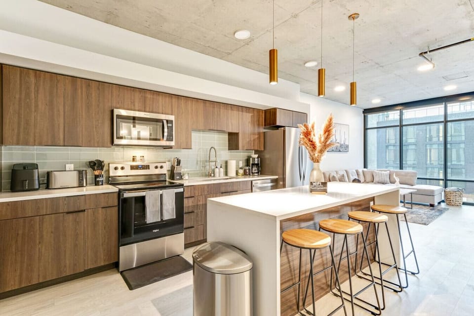 Modern kitchen with sleek cabinetry, island seating, stainless appliances, and open layout leading to the living space 🍳🥂✨