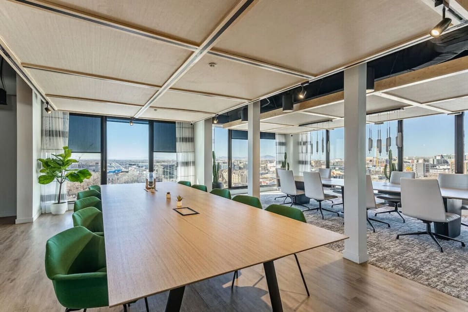 Bright meeting space w/ long table & skyline views through wraparound windows