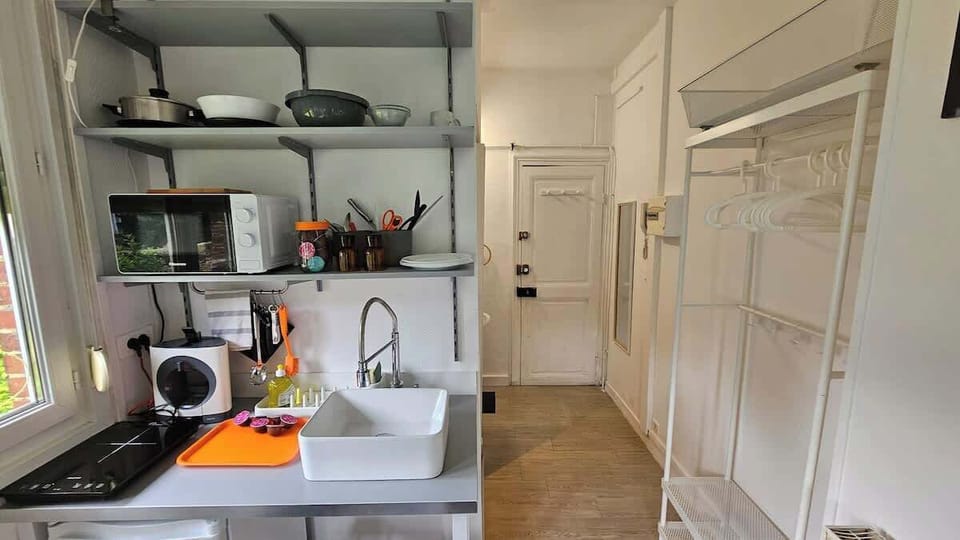 Kitchenette ouverte sur l'espace chambre, équipée avec plaque de cuisson, machine à café, micro-ondes et petit réfrigérateur.