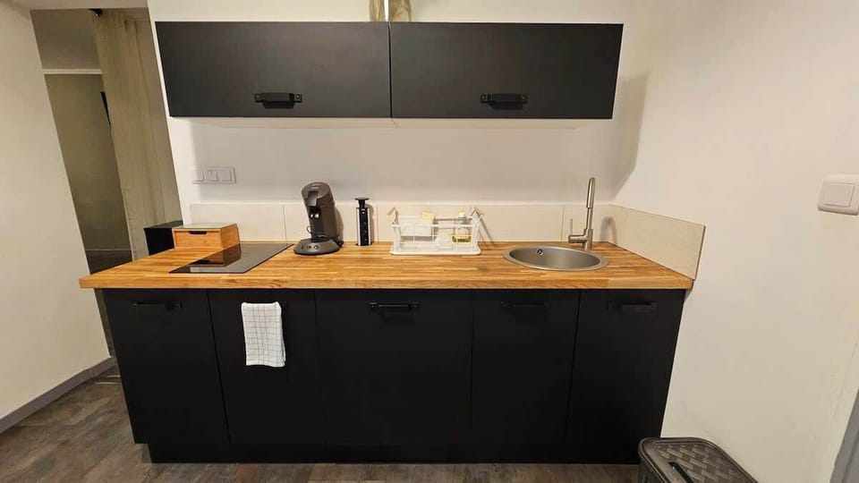 Cuisine équipée avec bouilloire, machine à café, plaques de cuisson, micro-ondes et petit réfrigérateur.
Table à manger pour deux personnes.