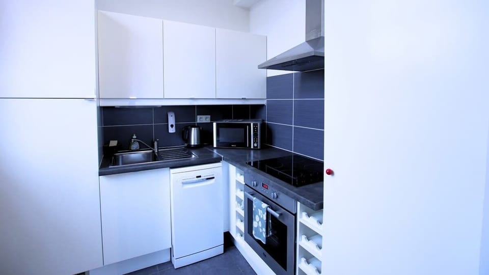 Cuisine équipée avec réfrigérateur avec freezer, lave-vaisselle, micro-ondes, machine à café, bouilloire, plaques de cuisson et four.