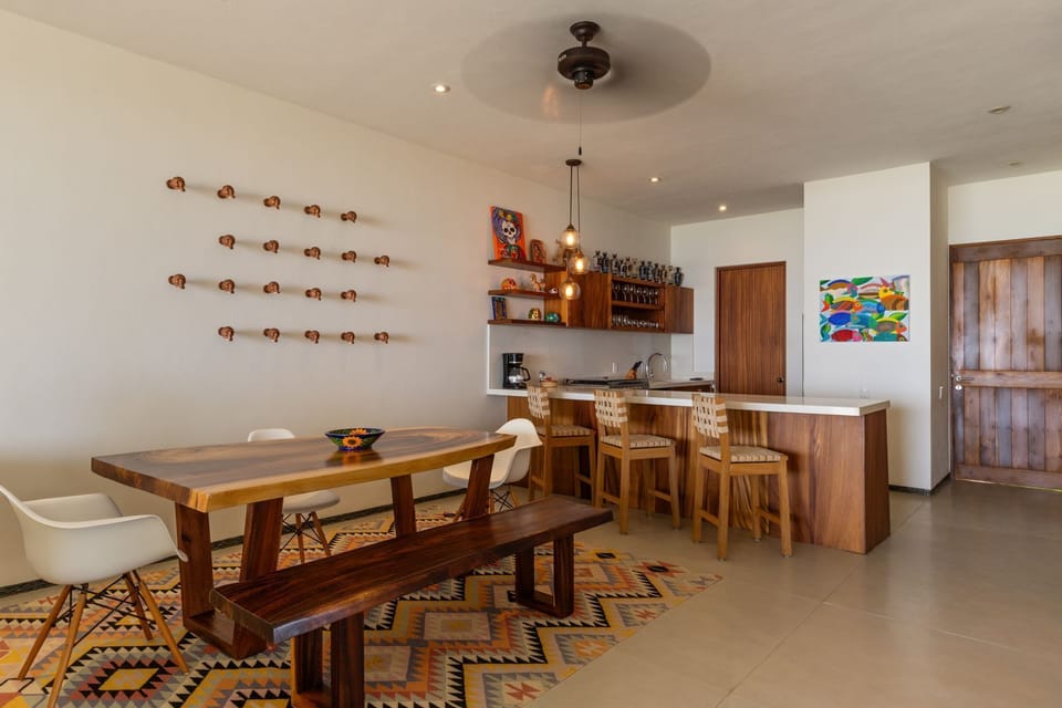 Enjoy meals in this modern dining area with handcrafted wooden accents, a fully equipped kitchen, and an ocean-inspired aesthetic.