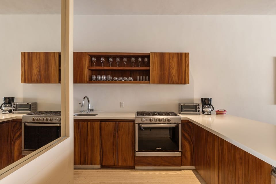 A fully equipped kitchen with rich wooden cabinetry, stainless steel appliances, and a sleek, minimalist design.