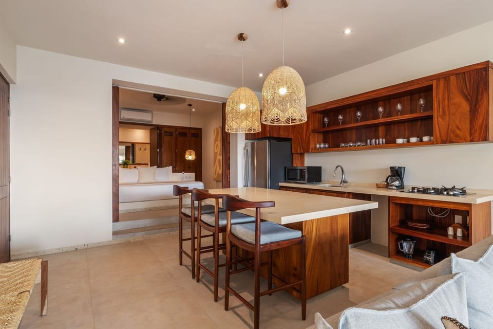 Enjoy a gourmet experience in this fully equipped kitchen with a sleek island, stylish wood finishes, and a spacious dining area with an ocean breeze.