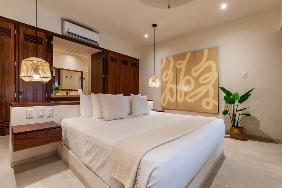 This bright and airy bedroom opens to lush tropical gardens, offering a peaceful sanctuary with luxurious linens and artistic decor.