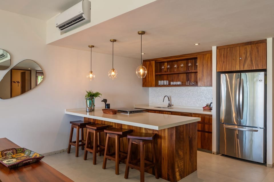 Cook and entertain effortlessly in this fully equipped kitchen with sleek wooden accents, pendant lighting, and bar seating.
