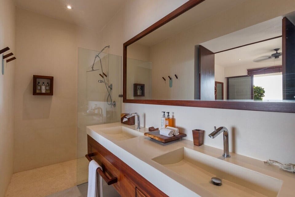 A spa-like bathroom featuring a sleek double vanity, rainfall shower, and stylish wooden accents.