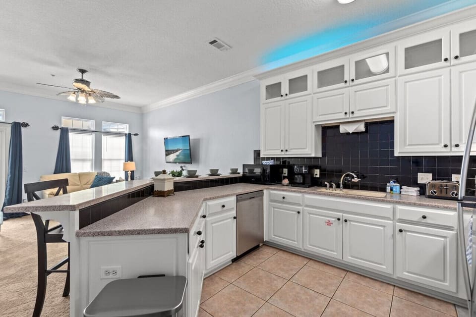 An updated kitchen with accent lights, a sleek breakfast bar, black tile back splash, and a central, inviting layout!