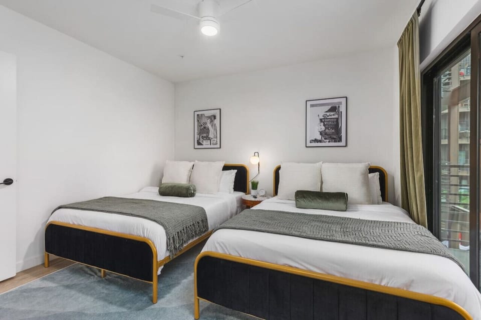 Two full-size beds in bedroom #2 with a Smart TV, room-darkening shades, ceiling fan, closet, connected bathroom, and a sliding door leading to the private balcony.