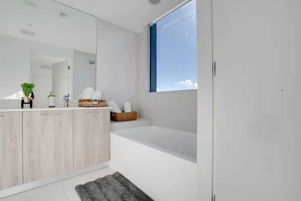 A modern en-suite bathroom complete with clean vanity storage and bright natural light.
