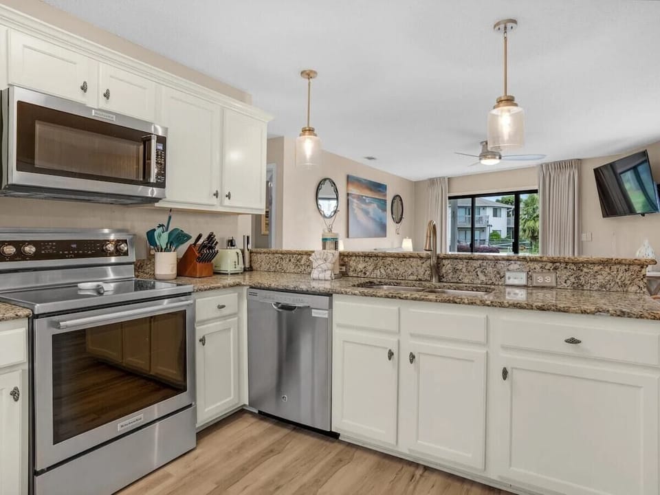 Full kitchen with dining area, fully equipped with cooking essentials. Features a breakfast bar with seating for 4.