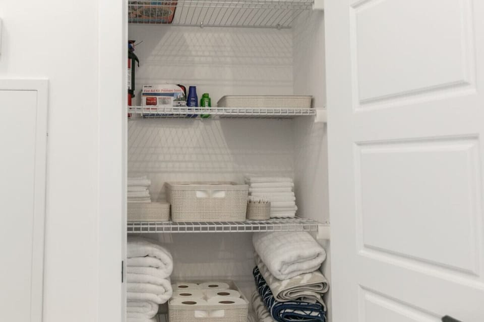 Cupboard stocked with essentials: fire extinguisher, first aid kit, and towels.