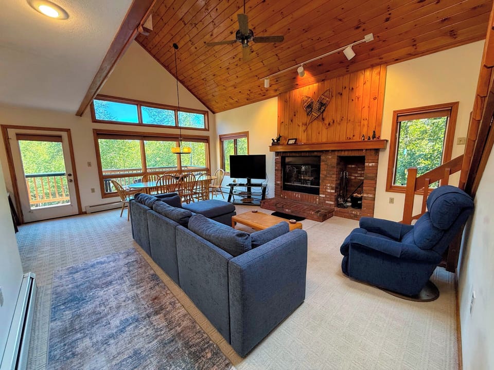 Main level living area with wood fireplace, TV with cable, and walkout to main level deck - adjacent to dining area and kitchen.