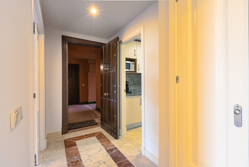 Apartment entrance hallway. To the right the door leading to the kitchen. To the left the doors leading to the open concept dinning, living room space with big sliding doors leading onto the terrace. Behind, the hallway leading beds and baths