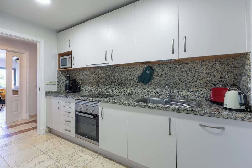 Fully furnished kitchen leading onto a laundry area. Kitchen equipped with oven, hob fridge freezer, washing machine, kettle, toaster, microwave, coffe maker.
