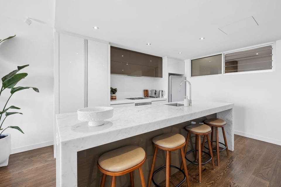 The kitchen is fully equipped and stylish, with stools at the island bench for casual meals