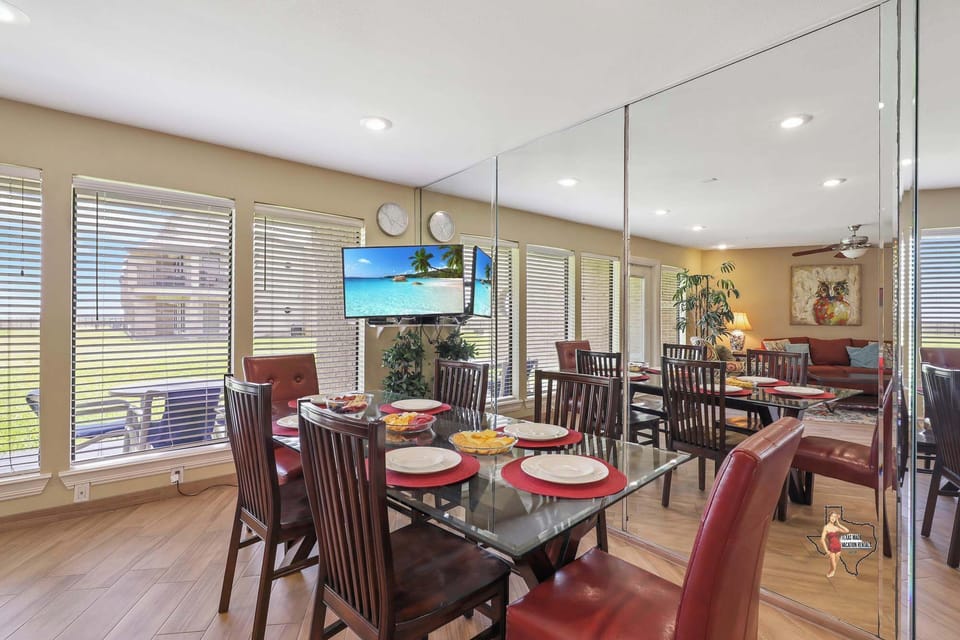 Elegant dining area with a large table set for six, featuring floor-to-ceiling windows and a mirrored wall to enhance the open feel.