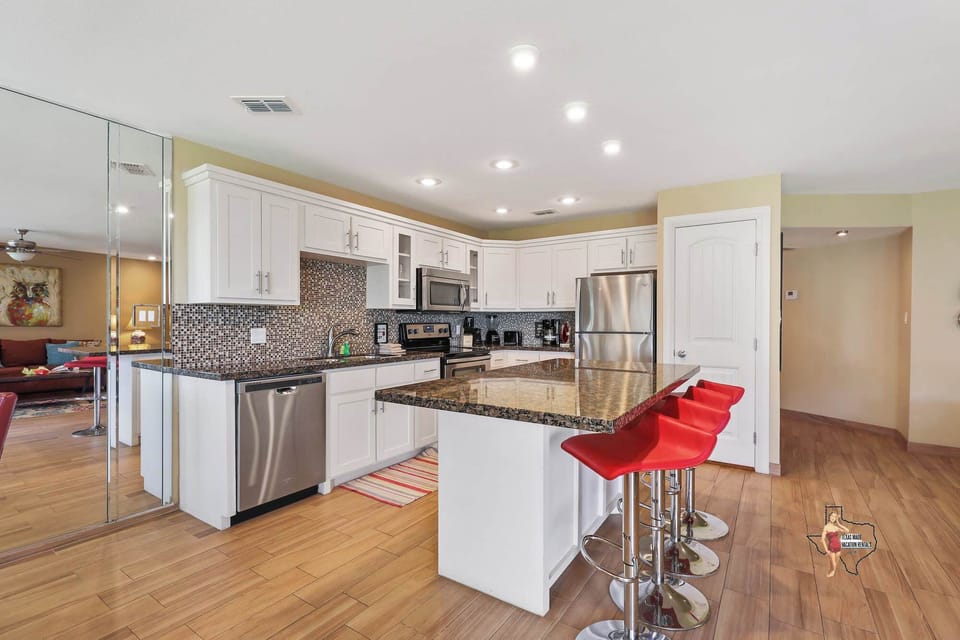Modern kitchen with sleek countertops, white cabinetry, and high-end appliances, including a kitchen island with bar seating.