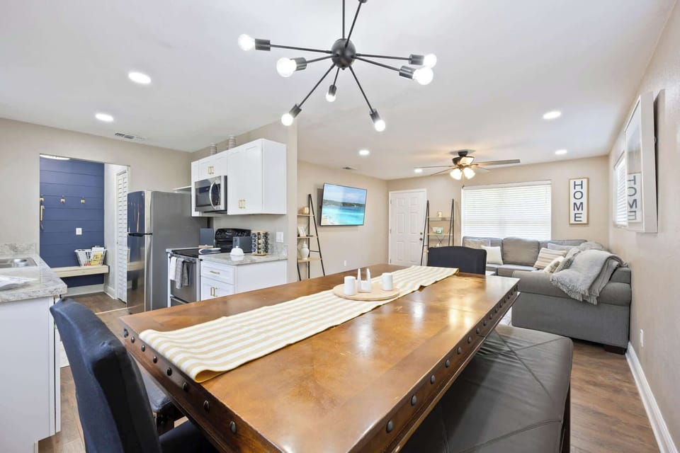 Open-concept living and dining area with modern lighting and a cozy sectional sofa.