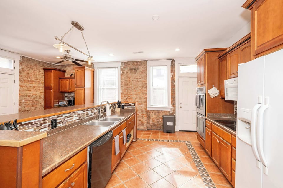 The kitchen showcases exposed brick, ample space, & numerous amenities