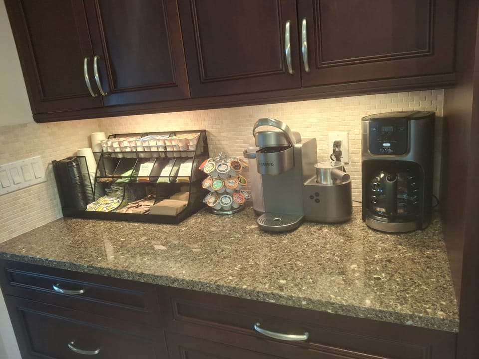 Fully stocked coffee bar with Keruig coffee maker, regular and flavored coffee, cappuccino steamer, and ten cup maker for a crowd