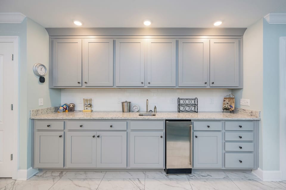 Grab a chilled drink from the fridge or create your favorite cocktail at the wet bar with sleek cabinetry and fun decor