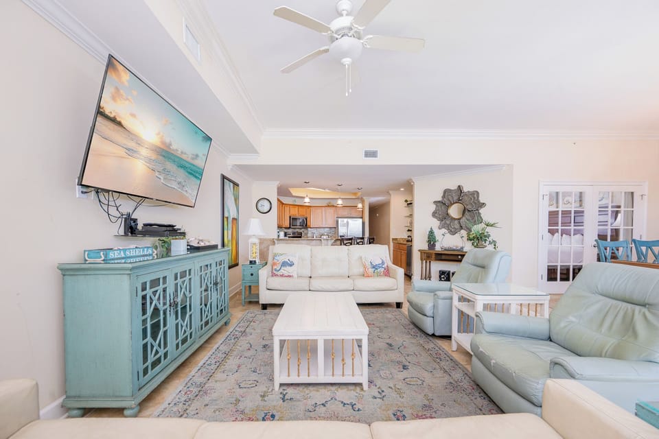 Bright and inviting living room featuring comfortable seating, a large TV, and an open view into the modern kitchen