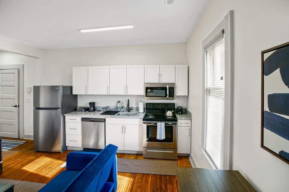Bright kitchen w/ white cabinets, stainless appliances & warm wood floors for easy meals at home
