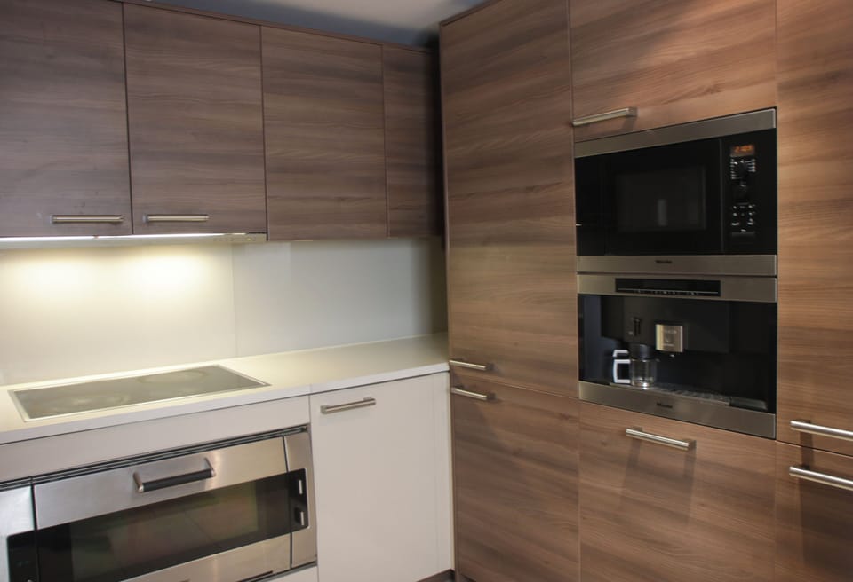 Modern kitchen with electric stove, extractor hood, LED lighting, and built-ins.