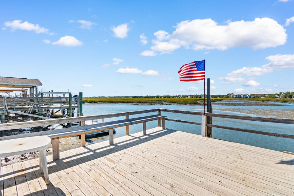 Private waterfront deck overlooking peaceful bay waters and distant coastal homes.