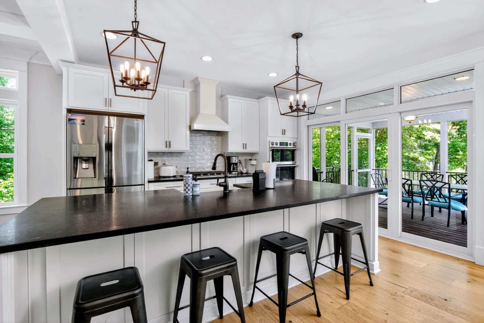 Kitchen - Ten-foot soapstone island, lantern pendants, and a wall of glass opening to the screened porch, this is where the day starts and ends.