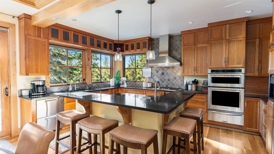 The heart of the home is a fully stocked chef's kitchen, complete with high-end appliances, ample counter space, and a large island with seating for five. Whether you're preparing a casual meal or hosting a holiday dinner, this kitchen is a cook's dream.