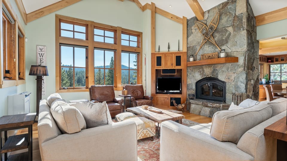 Enjoy the large, open-concept living room with a wood-burning fireplace and plush seating, creating a cozy space to gather with friends and family after a day on the slopes.
